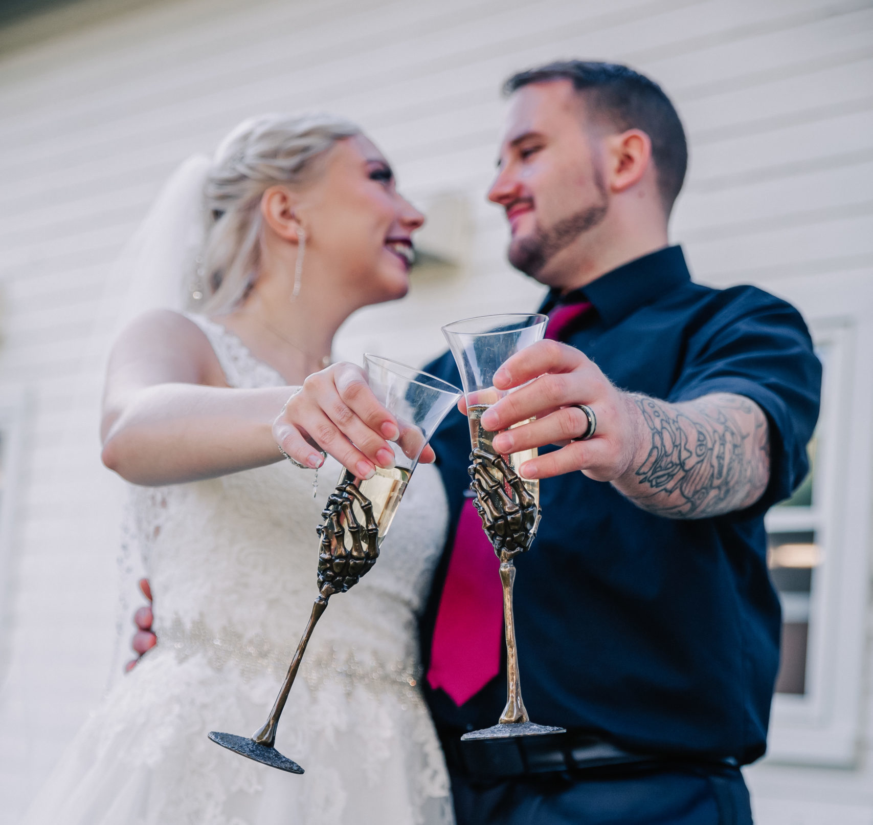 newly married couple clinking skeleton hand champagne glasses, one of many fun and unique items at their New England wedding