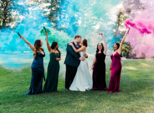 wedding party posing on green with smoke bombs at Blue Hill Country Club in Canton, MA