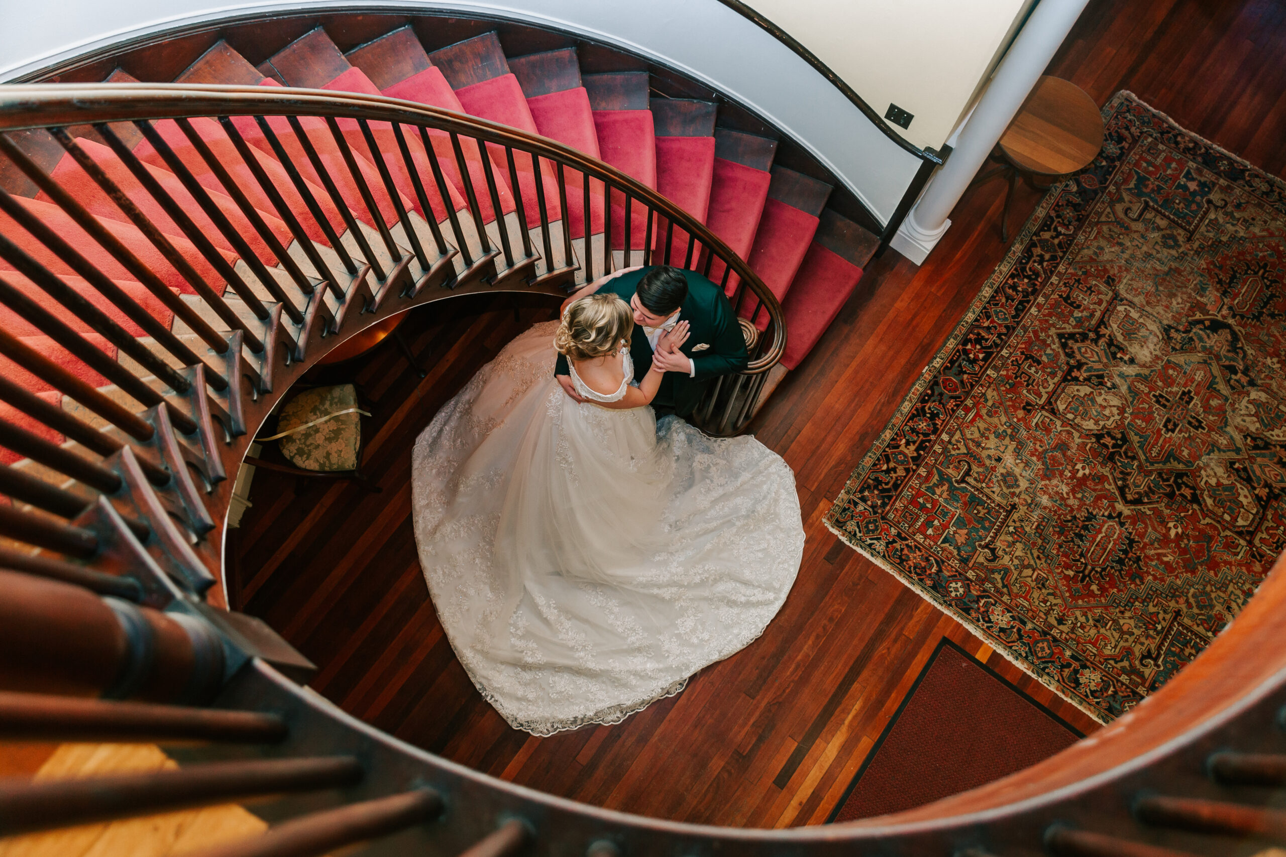 same-sex couple kissing by elegant staircase after their first look at Linden Place, a gorgeous Rhode Island wedding venue, on their wedding day