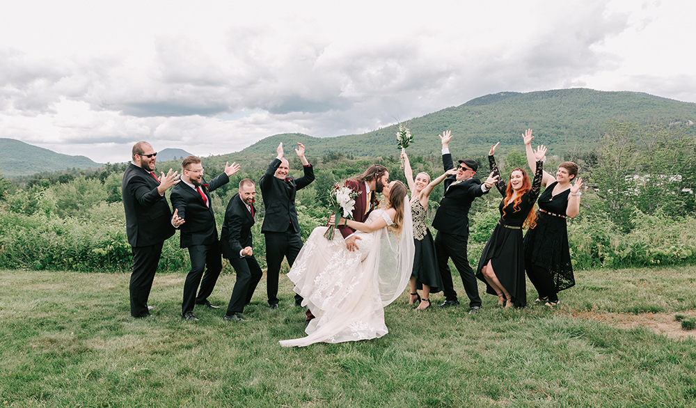 newly married bride and groom posing with wedding party at a White Mountains wedding venue