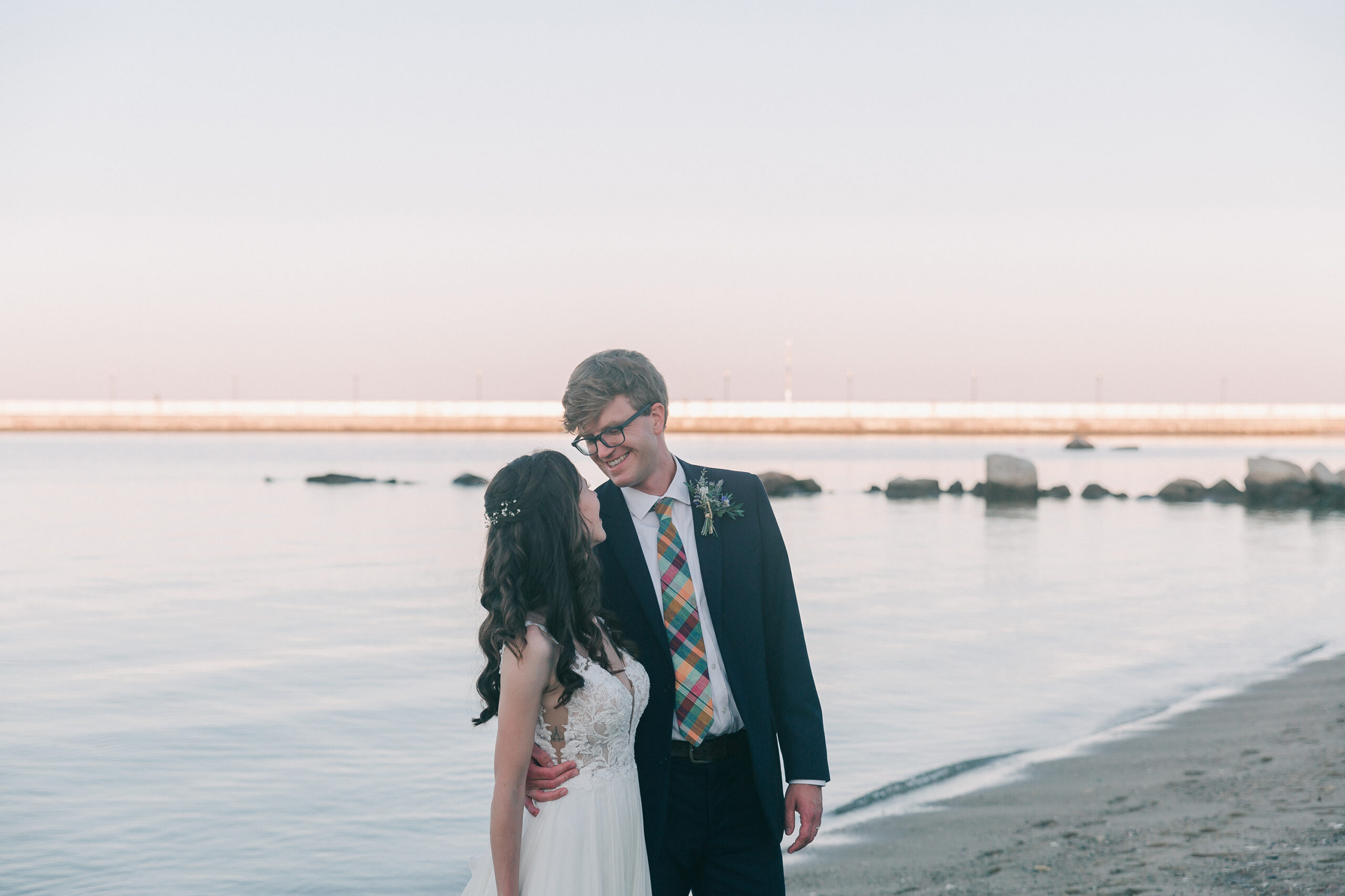 newlywed couple posing for sunset photos on the beach after their wedding, planned by Cose Bella Events, a Rhode Island wedding planner 