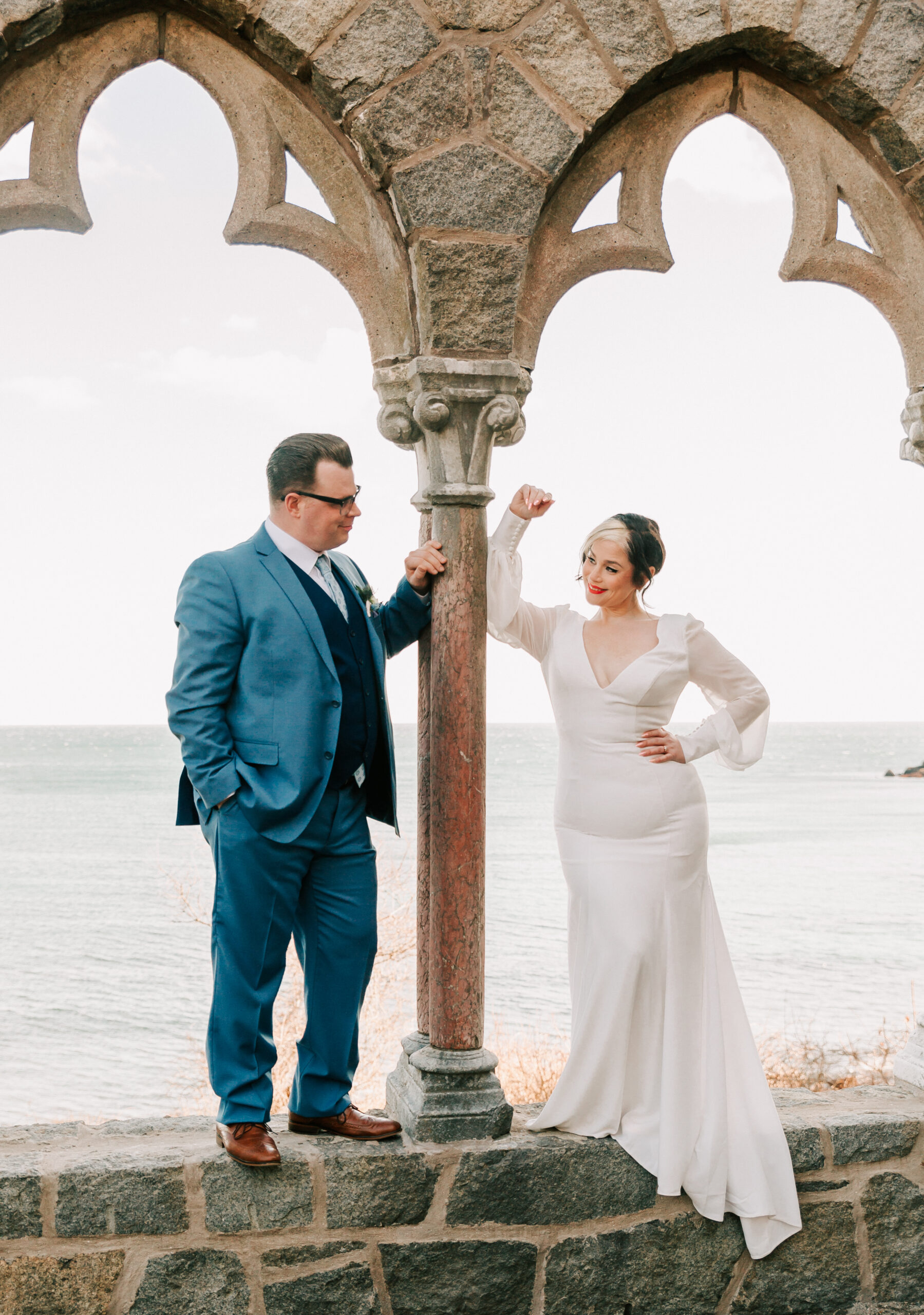 bride and groom posing by columns at Hammond Castle, wearing attire from Thistle Rose Bridal, a Boston wedding dress shop