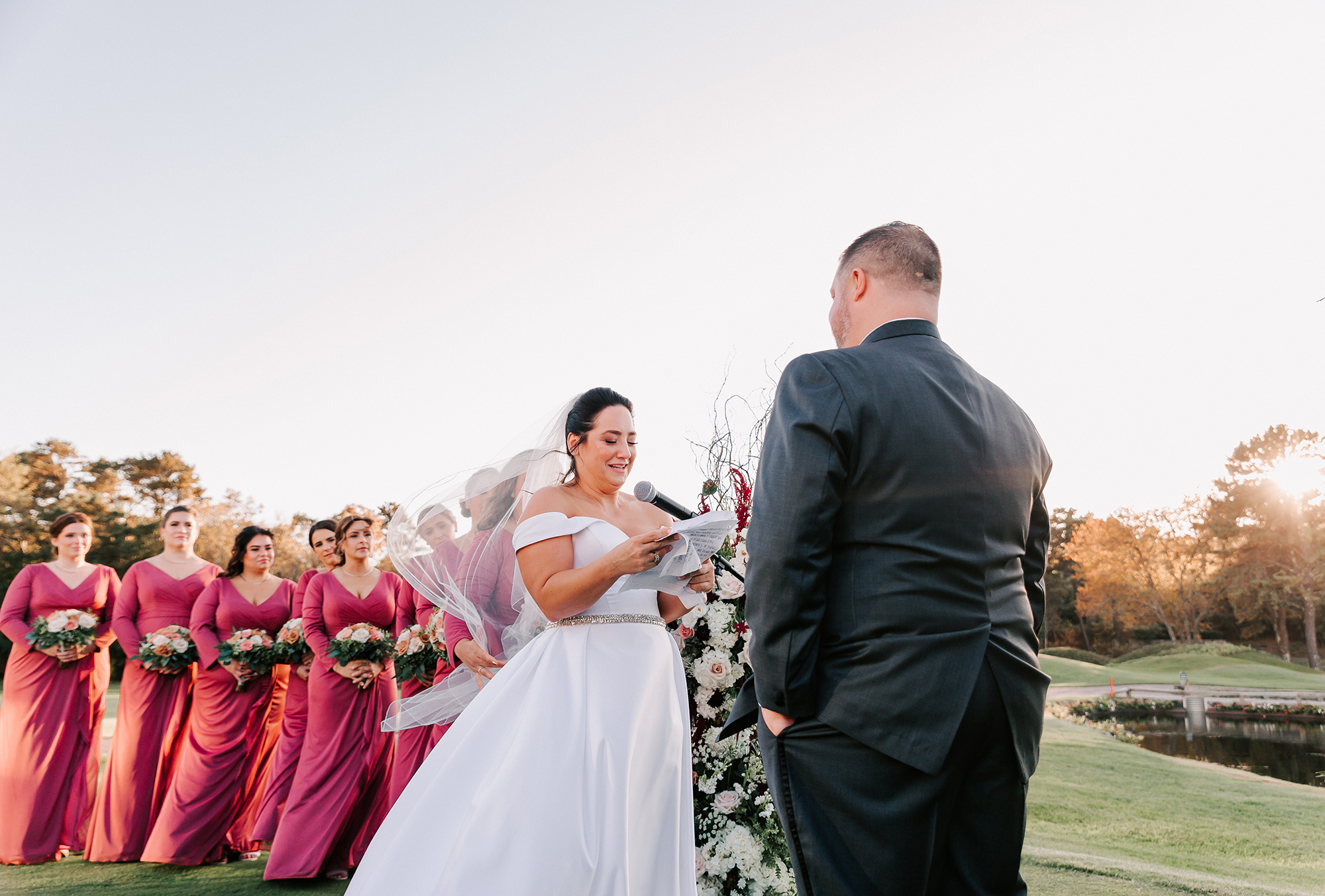 bride reading her vows to groom during sunset ceremony on lawn at Willowbend Country Club