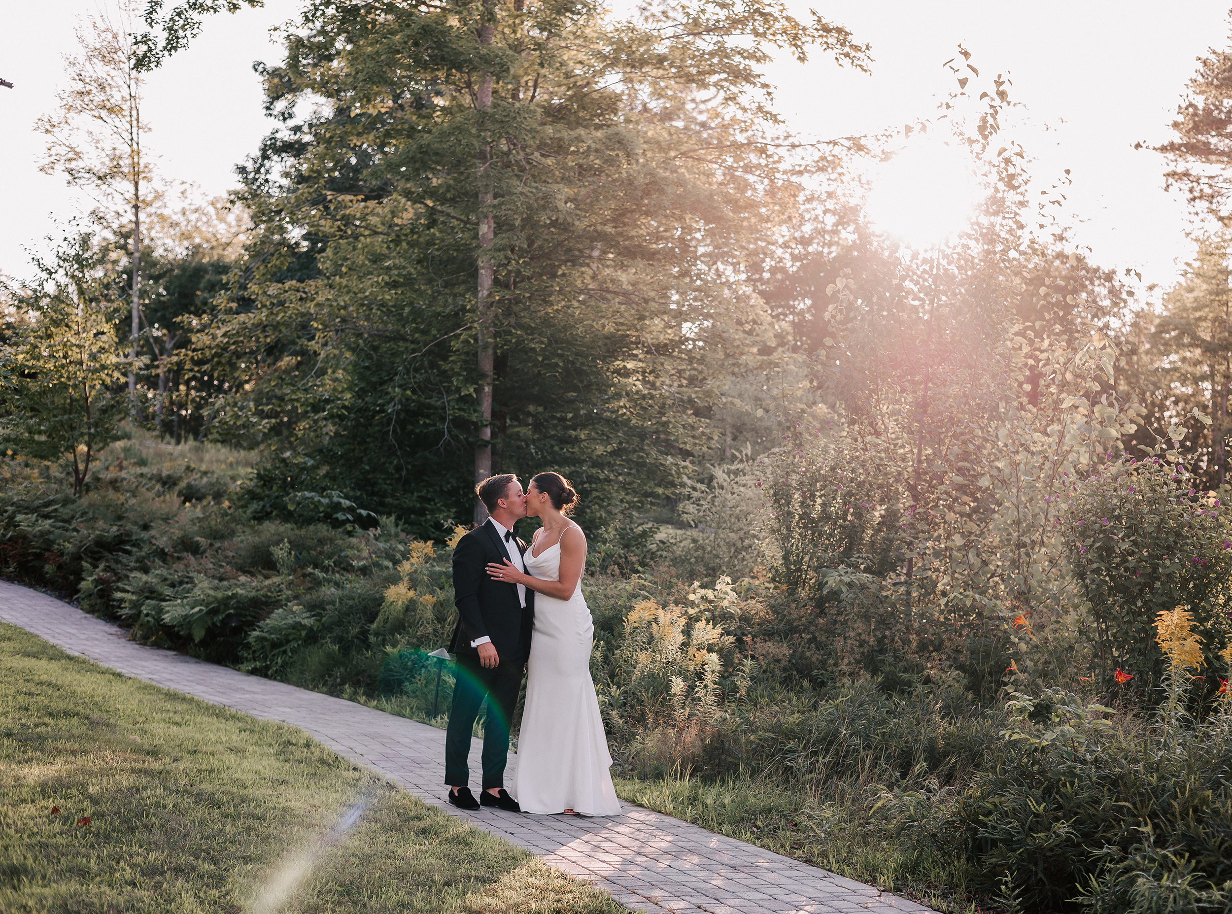 bride and groom kissing walking down path at Autumn Lane Estate, one of the top Maine wedding venues