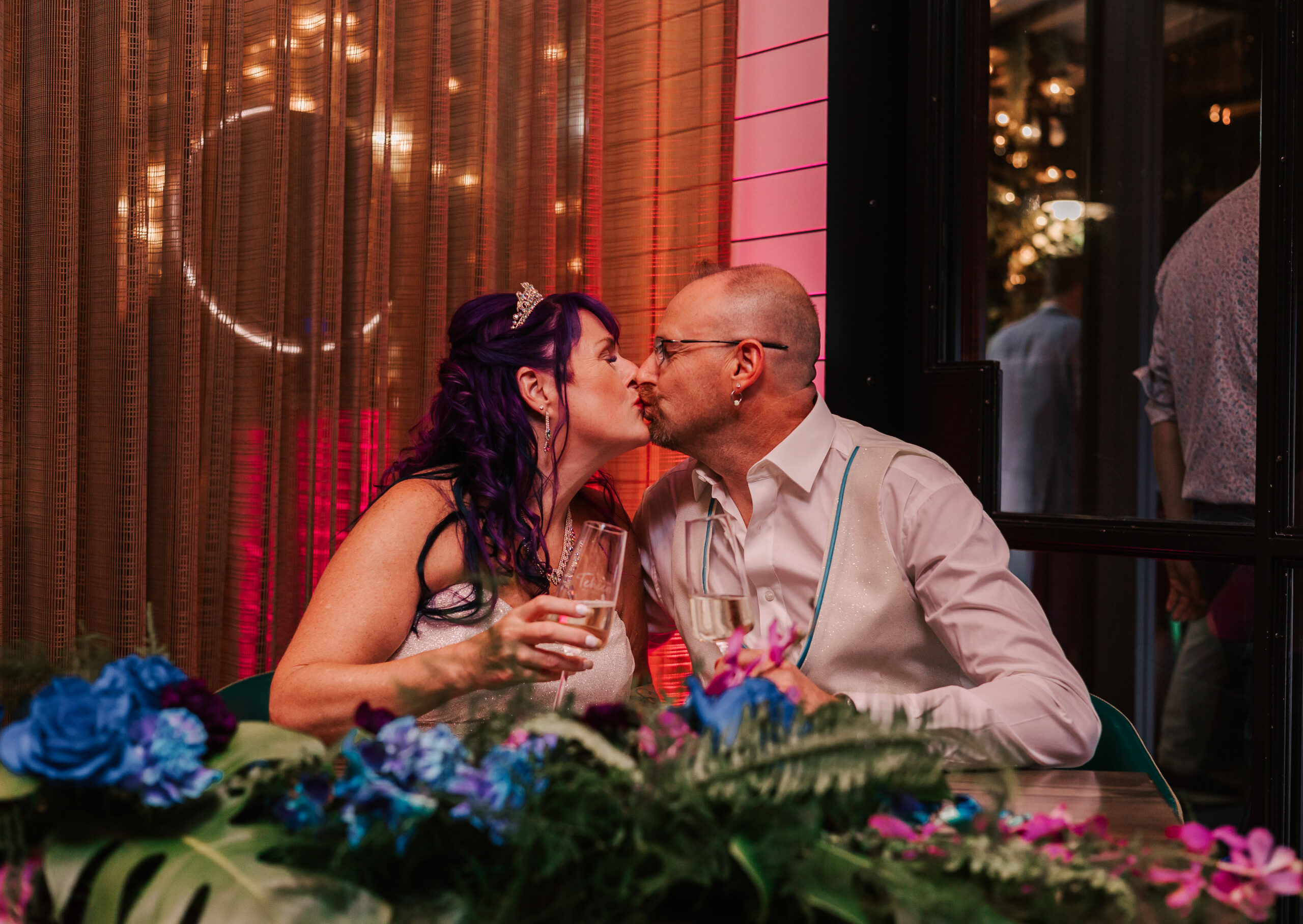 newly married couple kissing at sweetheart table at their wedding reception at Glass House