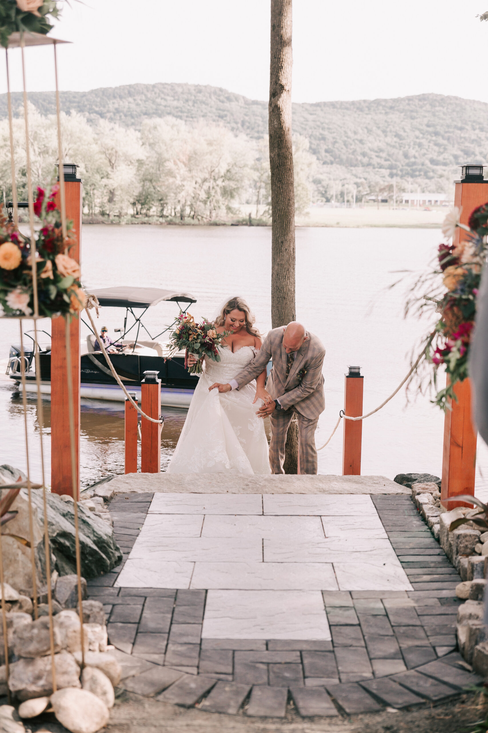 bride arriving at wedding ceremony by boat, sailing toward the dock at her backyard wedding